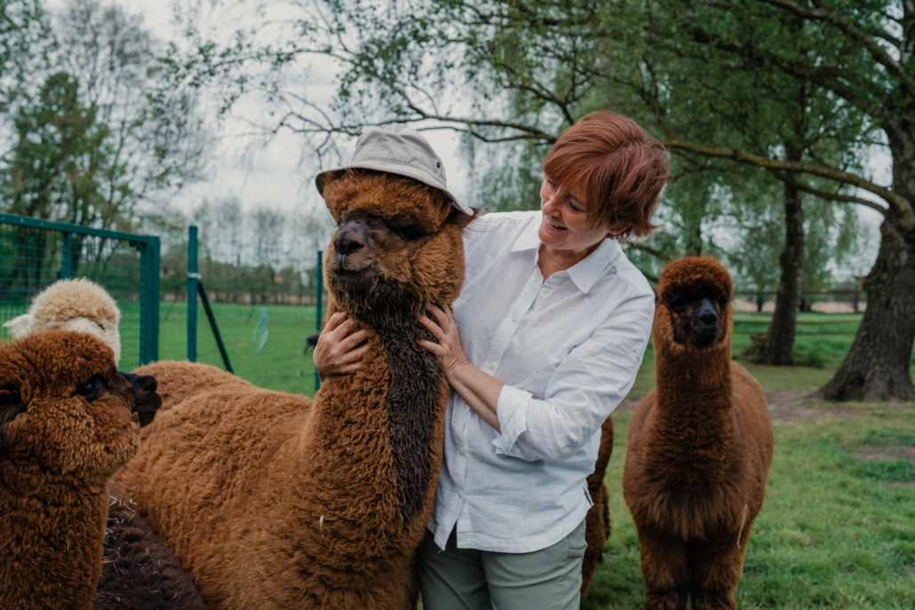 Alpaca met hoedje en lachende boerin